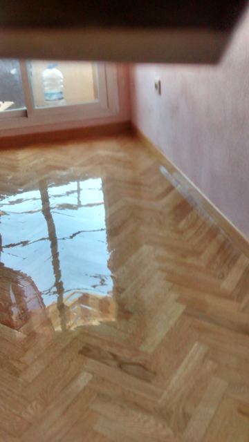 Parquet al hilo barnizado con reflejo de la ventana